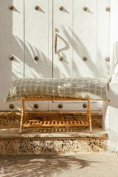 a wooden bench sitting in front of a white wall with lots of holes on it