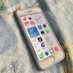 an iphone sitting on top of a bed next to a flowery blanket and pillow