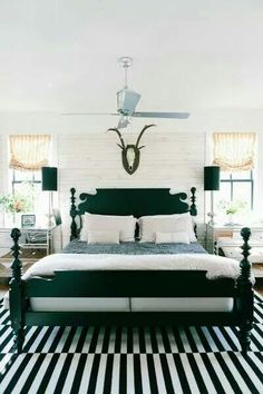 a bedroom with black and white striped flooring and a bed in front of a ceiling fan