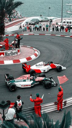 two racing cars on a race track with people watching