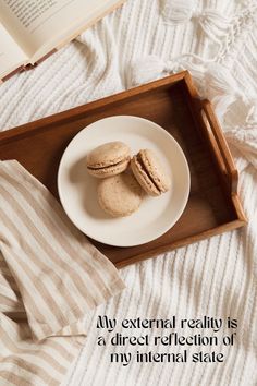 two macaroons are on a plate next to an open book and a pillow