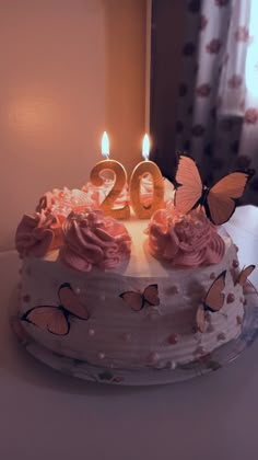 a birthday cake with two candles and butterflies on it