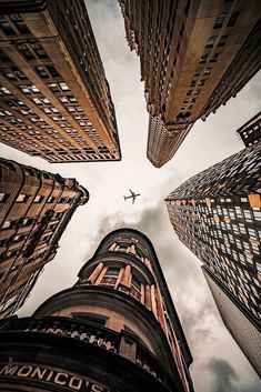 an airplane flying through the sky between two tall buildings