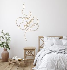 a bed room with a neatly made bed next to a table and plant on the floor