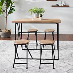 three stools and a table in the middle of a room with a potted plant