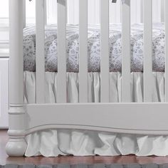 a white baby crib with ruffled bedspread