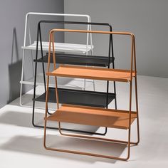 three metal and wood trays stacked on top of each other in an empty room