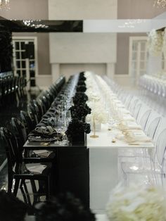 a long table is set with black and white chairs for an event or wedding reception