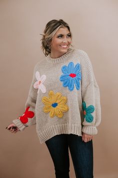 a woman wearing a sweater with flowers on it