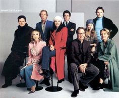 a group of people sitting next to each other in front of a white wall and chair