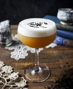 a drink sitting on top of a wooden table next to a lace doily and books