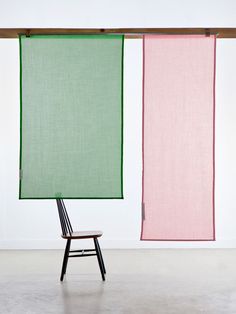 a chair sitting in front of two green and pink vertical blinds hanging from the ceiling