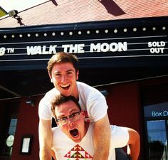 two men in front of a theater with their mouths open and one man on his back