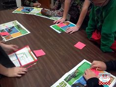 several children sitting around a table with cards and papers in front of them on the table