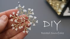 a hand holding a beaded snowflake ornament