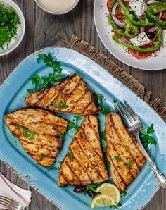 grilled chicken on a blue platter with salad and dressing next to the plate