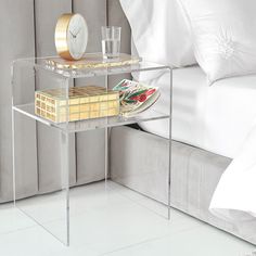 a bed with a white comforter and a clear side table