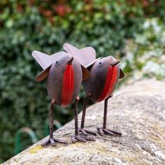 two metal birds standing on top of a rock