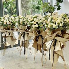 three vases filled with white flowers sitting on top of each other in front of a window