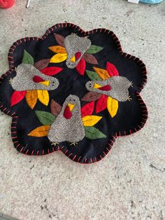 a black mat with birds on it sitting on the floor next to a pair of scissors