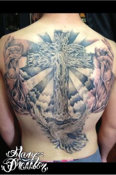 the back of a man's chest with tattoos on it and an image of a cross