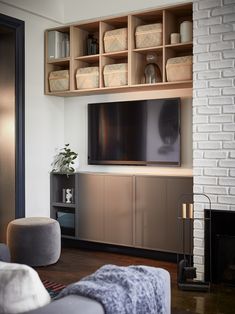 a living room with white brick walls and wooden shelving units, including a large flat screen tv