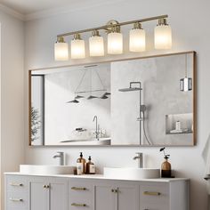 a bathroom vanity with two sinks and three lights on the mirror above it is shown