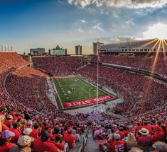 a football stadium filled with lots of red and white people sitting on the bleachers