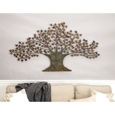 the metal tree is hanging on the wall next to a white couch and throw pillow