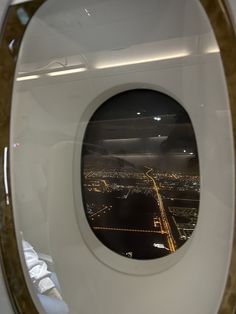 an airplane window with the city lights seen through it's portholes at night