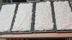 four pans filled with rice sitting on top of a wooden table