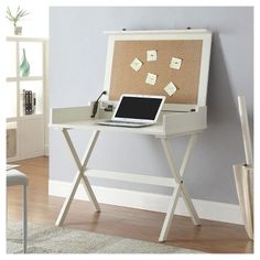 a laptop computer sitting on top of a white desk in front of a cork board