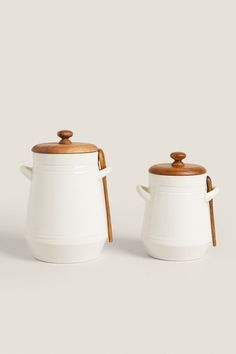 two white ceramic containers with wooden lids