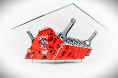 a red engine block sitting on top of a white table next to a glass shelf