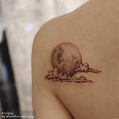 a woman's shoulder with a small tattoo of a moon and clouds on it