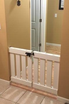 a hallway with a white railing and mirror on the wall, in front of a tiled floor