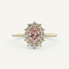 an oval pink diamond surrounded by small white and yellow diamonds on a gold band ring