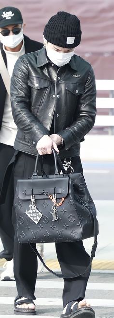 a man wearing a mask and holding a black handbag