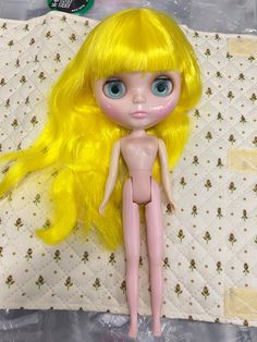 a doll with blonde hair and blue eyes laying on a quilt