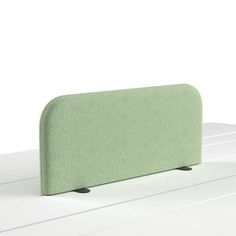 a green headboard sitting on top of a white table next to a black object