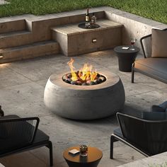 a fire pit sitting on top of a cement floor next to some chairs and tables