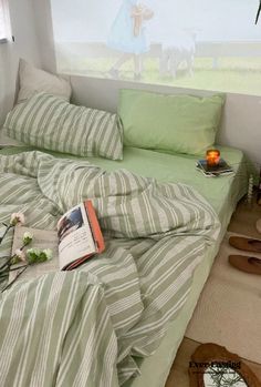 a bed with green and white striped sheets in a bedroom next to a painting on the wall