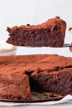 a piece of chocolate cake being held by a spatula over the top of it