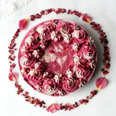 a cake with pink frosting and flowers around it