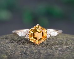 an orange sapphire and diamond ring sitting on top of a rock