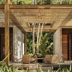 an outdoor covered patio with wicker furniture and trees in the backgrouds