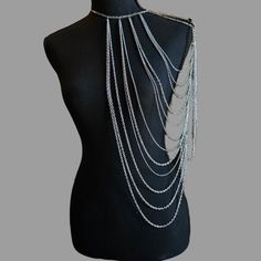 Introducing the majestic Silver Queen Body Chain, a stunning accessory that exudes elegance and strength. This remarkable body chain is meticulously designed to drape over the left shoulder, creating a captivating and empowering statement. Embrace your inner warrior queen and make a bold fashion statement with this extraordinary piece. The Silver Queen Body Chain features an intricate arrangement of looping chains of various sizes, symbolizing the unyielding spirit and resilience of a true queen. Its design reflects the perfect balance between elegance and strength, capturing the essence of a powerful and fearless leader. Crafted with meticulous attention to detail, the Silver Queen Body Chain is a testament to the craftsmanship and quality that goes into each piece. It is made from high-q Full Body Jewellery, Silver Adjustable Body Chain For Festivals, Bohemian Body Jewelry With Chain Strap, Silver Clavicle Chain Body Jewelry For Festival, Silver Clavicle Chain Body Chain For Festival, Silver Clavicle Body Chain For Festivals, Silver Body Jewelry With Clavicle Chain For Festival, Silver Body Chain With Clavicle Detail For Festival, Silver Body Chain With Chain Strap For Evening