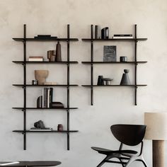 a black chair sitting in front of a wall mounted book shelf with books on it