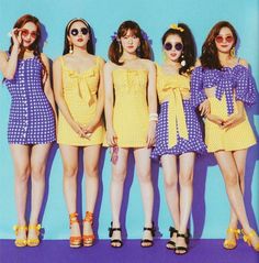 four girls in yellow and purple dresses posing for the camera with sunglasses on their heads