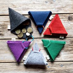 four small felt triangles sitting on top of a wooden table next to some pennies